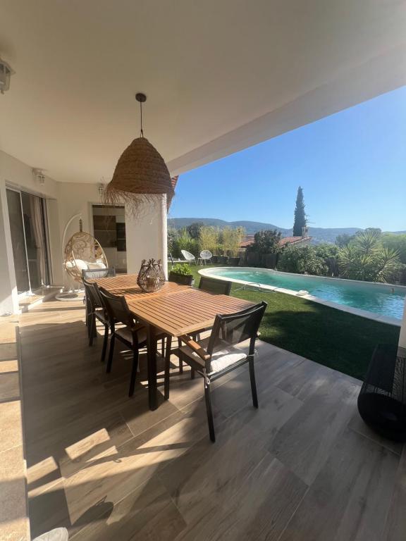 une table et des chaises en bois sur une terrasse avec une piscine dans l'établissement Villa Gessica, à Draguignan