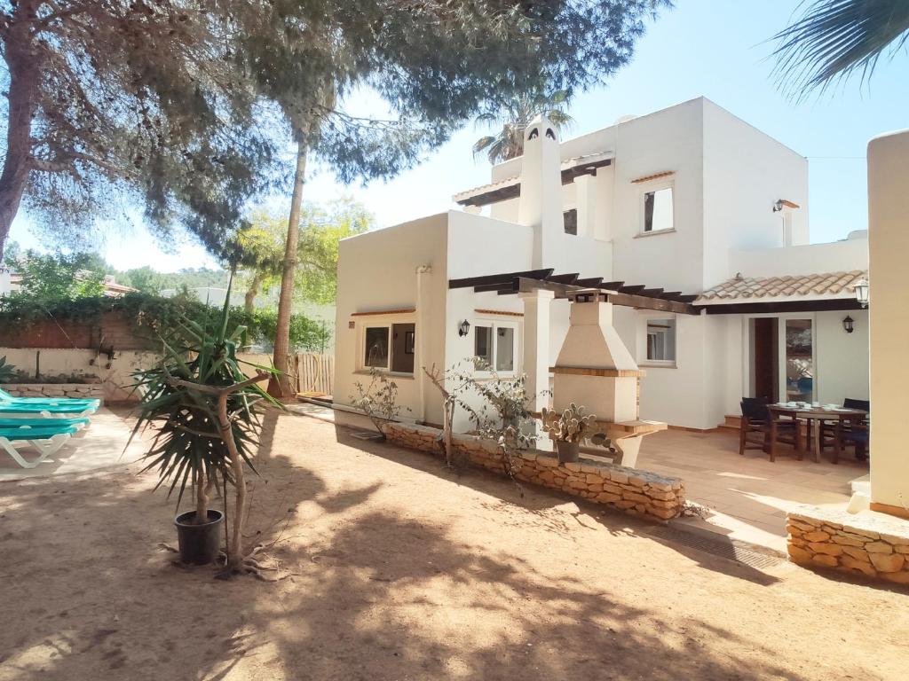 uma grande casa branca com um quintal e um pátio em Casa Rainer em Es Figueral Beach