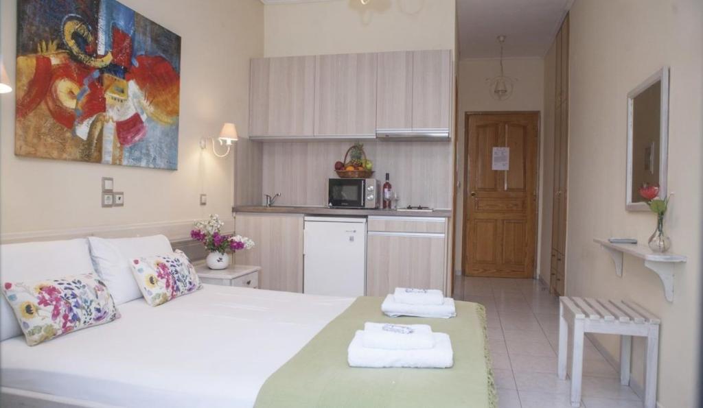 a bedroom with a white bed and a kitchen at Nontas Home in Kalamitsi