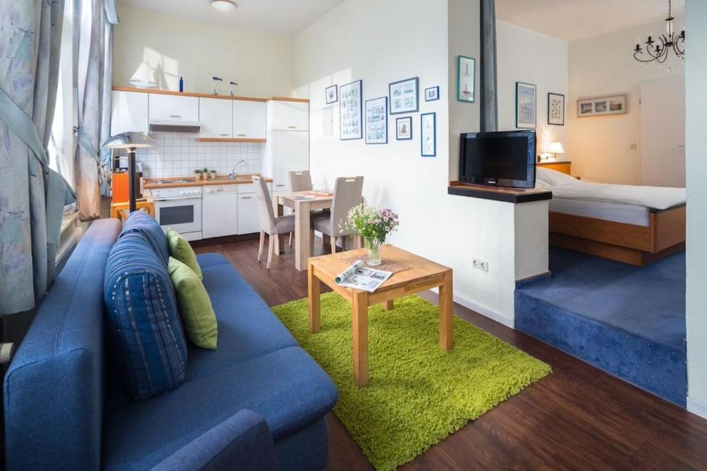 a living room with a blue couch and a small table at Strandkorb in der Villa Medici in Norderney