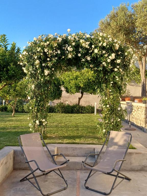 two chairs sitting under an arch with white flowers at La Casa di Pitti in Anacapri