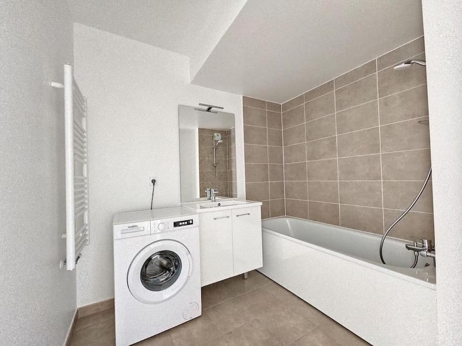 ein Badezimmer mit einer Waschmaschine und einer Badewanne in der Unterkunft Charme Citadin in Villemomble