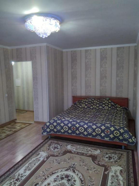 um quarto com uma cama e um lustre em 1 комн. квартира на Есет батыра em Aqtöbe