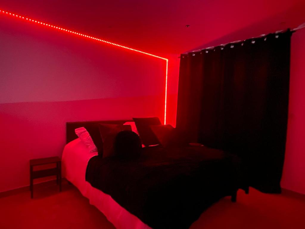 une chambre avec un lit avec une lumière rouge dans l'établissement Love Room avec Baignoire Balnéo Jacuzzi, à Saint-Étienne