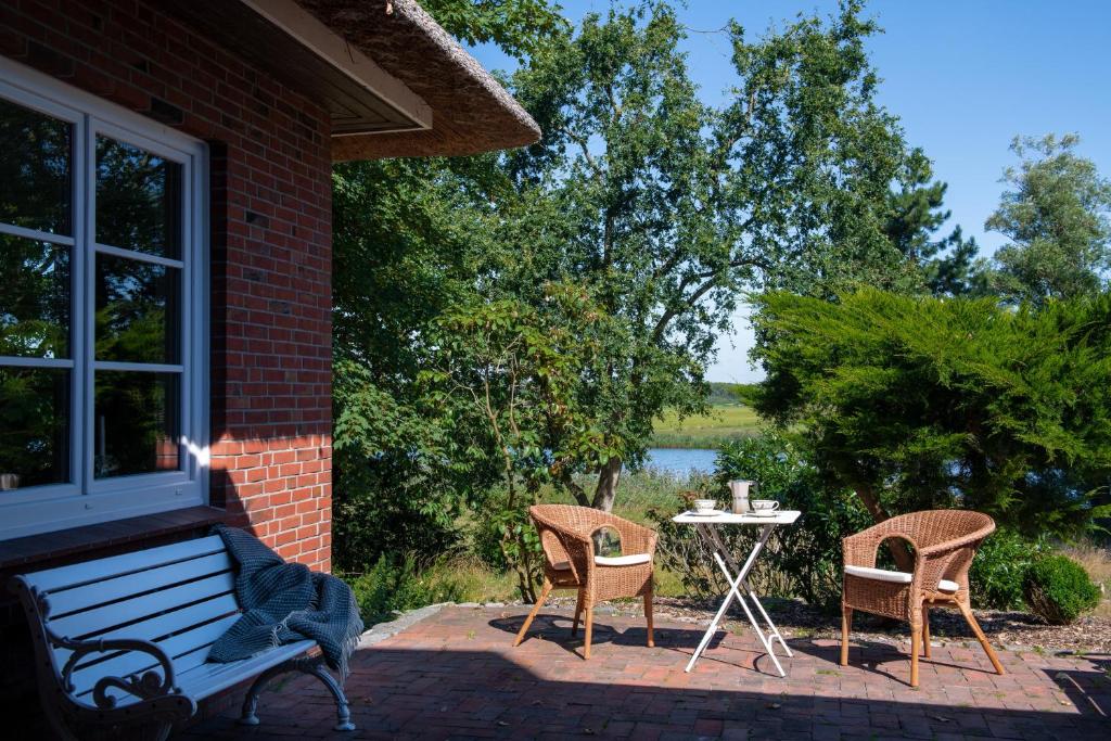 a patio with a bench and a table and chairs at Reetdachhaus Eiderblick in Breiholz