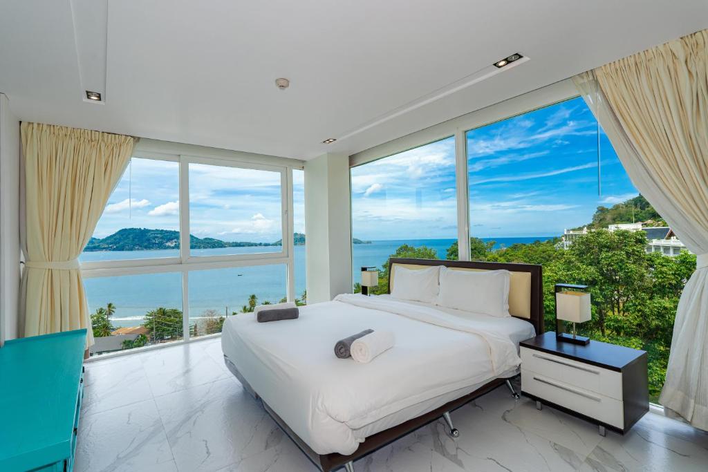 芭东海滩Patong Kalim Unparalleled Sea View B&B Resort的一间配有大床和大窗户的卧室