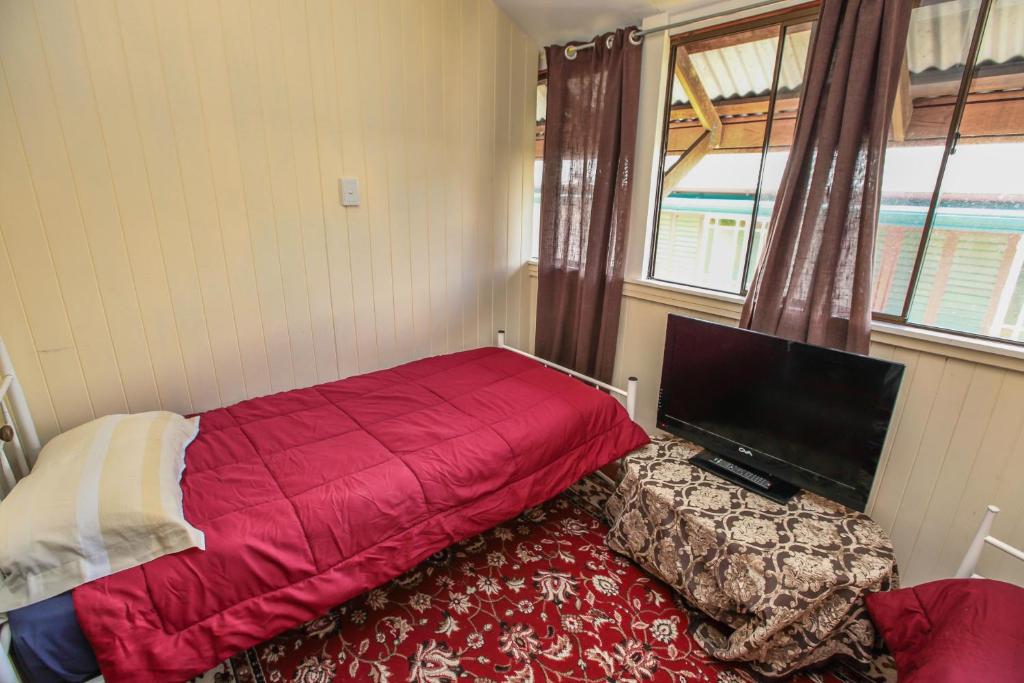 a bedroom with a red bed and a flat screen tv at Ryan's Rest Boutique Accommodation in Cairns