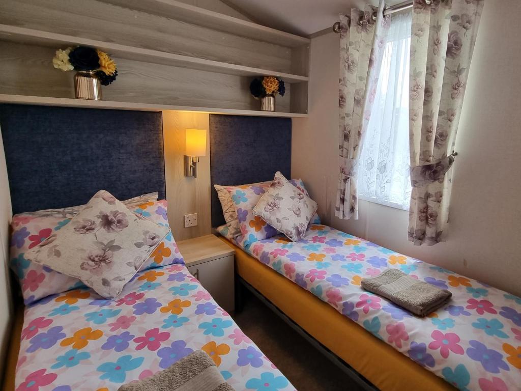 1 dormitorio con 2 camas y ventana en Static Caravan to Hire , Hoburne Devon Bay ( Paignton), en Goodrington