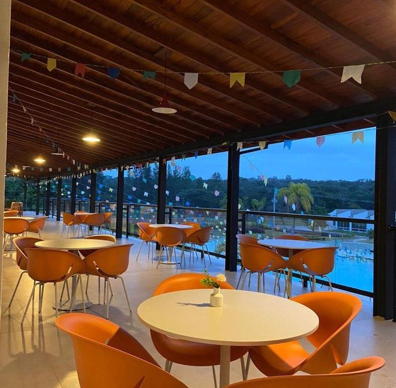 um restaurante com mesas e cadeiras e vista para uma piscina em Vale Das Águas Fazenda Resort em Águas de Santa Barbara