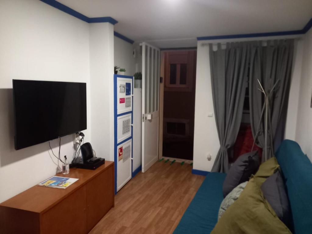 een woonkamer met een bank en een tv bij Casa da Mariquinhas in Lissabon