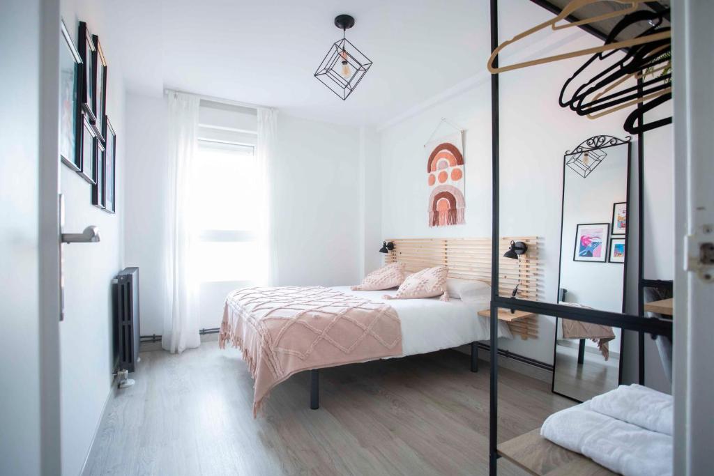 - une chambre blanche avec un lit et un miroir dans l'établissement Acogedor apartamento con vistas a la basílica y 2 plazas de garaje, à Saragosse