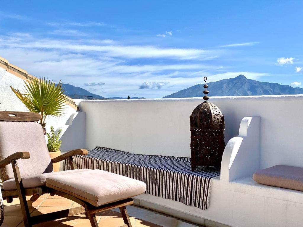 balcón con cama, silla y montañas en Duplex vistas al golf Guadalmina Marbella, en Marbella