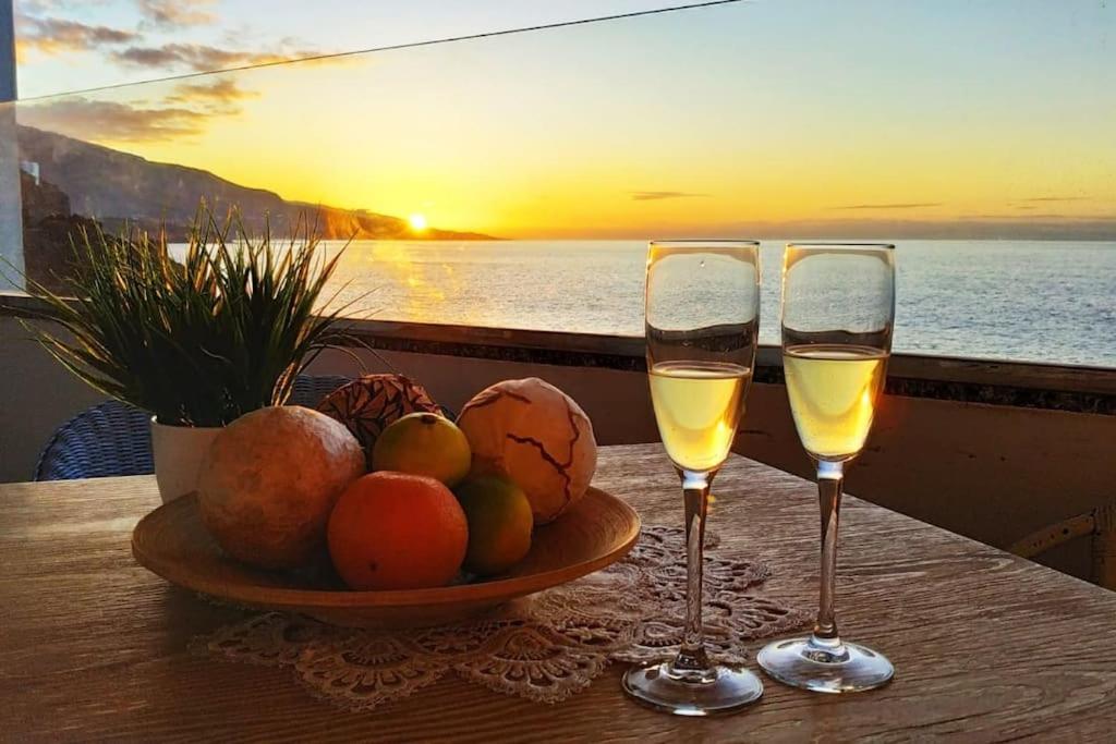 two glasses of wine on a table with a bowl of fruit at Ocean Orchidea in Puerto de la Cruz