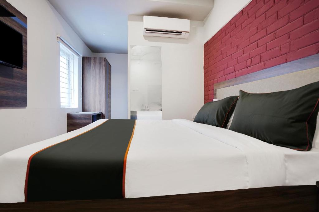 a bedroom with a white bed with a red brick wall at Hotel Kalinga Bapuji Nagar in Bhubaneshwar