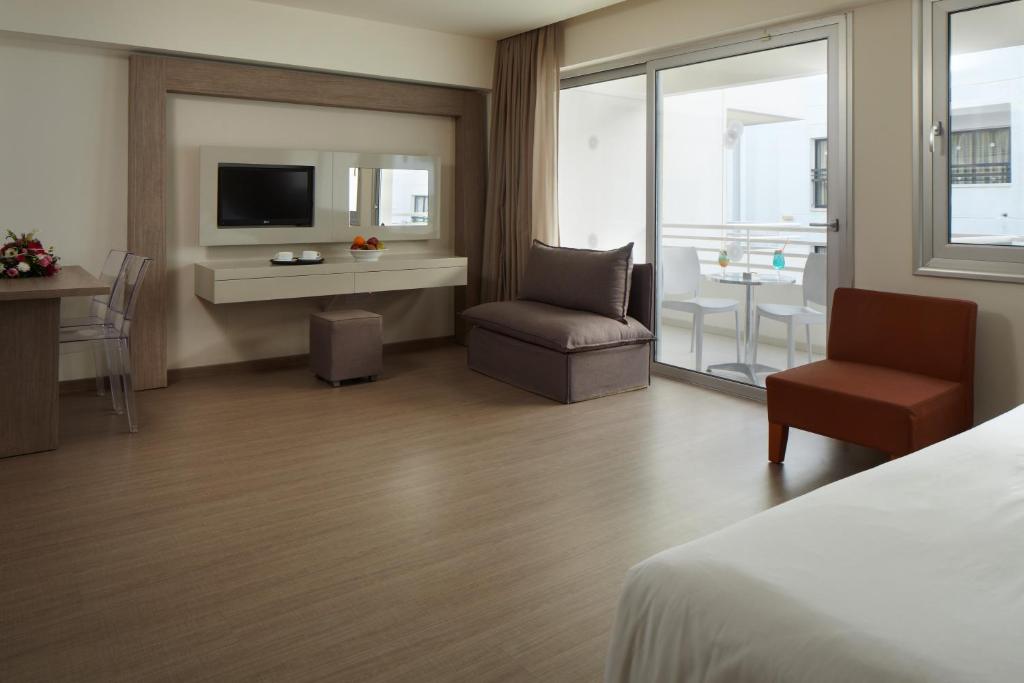 a hotel room with a bed and a chair and a television at Melpo Antia Hotel & Suites in Ayia Napa