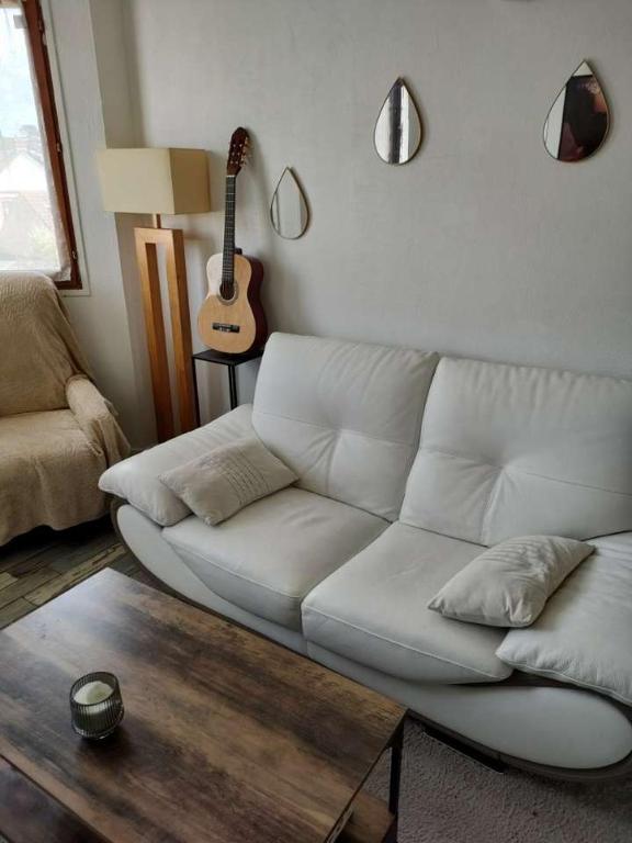 - un salon avec un canapé blanc et une guitare dans l'établissement Appartement proche plage, à Ouistreham