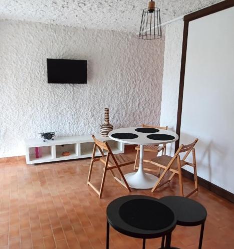 une pièce avec une table, des chaises et une télévision dans l'établissement Appartement T1 cabine proche plage, à Lumio