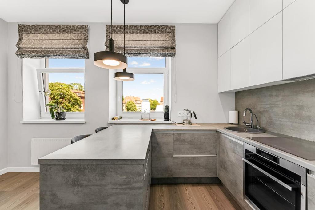 eine Küche mit weißen Schränken und einer grauen Arbeitsplatte in der Unterkunft Old town apartment Klaipėda free parking in Klaipėda