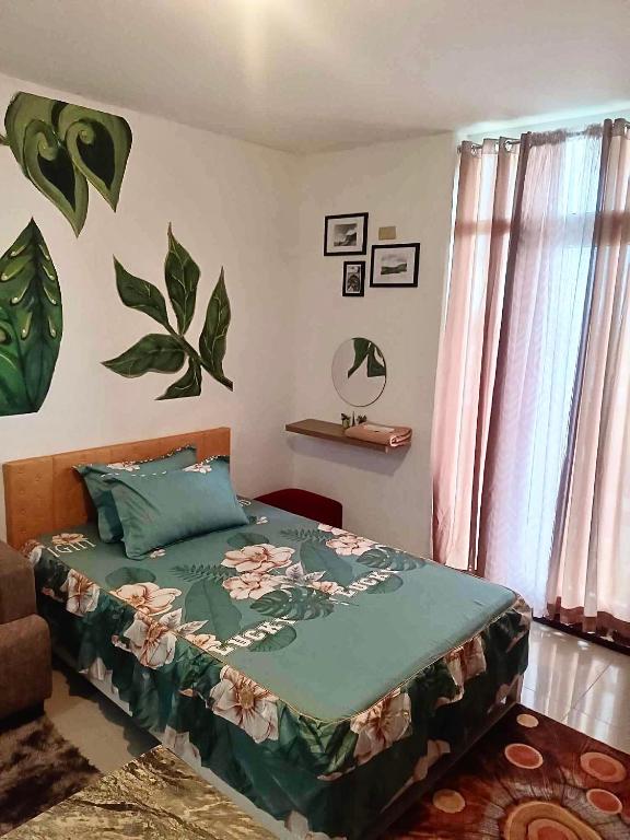 a bedroom with a bed with a green comforter at Pamz Studio Condo Unit in Lapu Lapu City