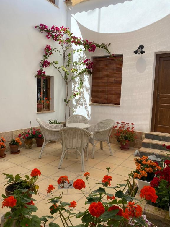 un patio con mesa, sillas y flores en Casa Cordón, en Montilla
