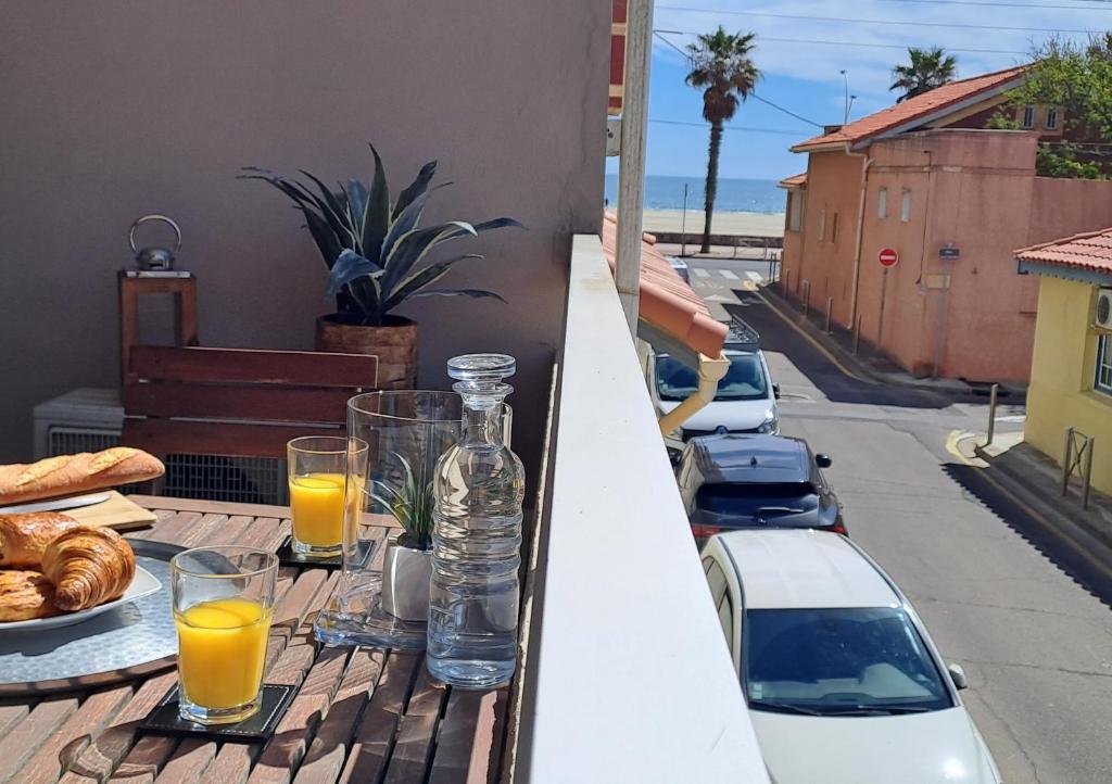 - une table avec des verres de jus d'orange et du pain sur un balcon dans l'établissement T2 vue mer Climatisé à 40m de la plage, à Canet