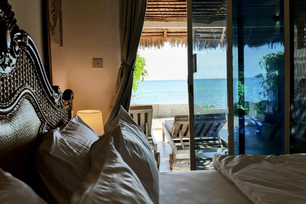 a bedroom with a bed and a view of the ocean at Lala Land Lodge in Kizimkazi