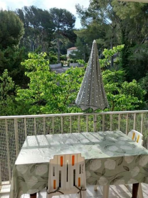 d'une table, de chaises et d'un parasol sur le balcon. dans l'établissement Les Aigues Marines, à Saint-Cyr-sur-Mer