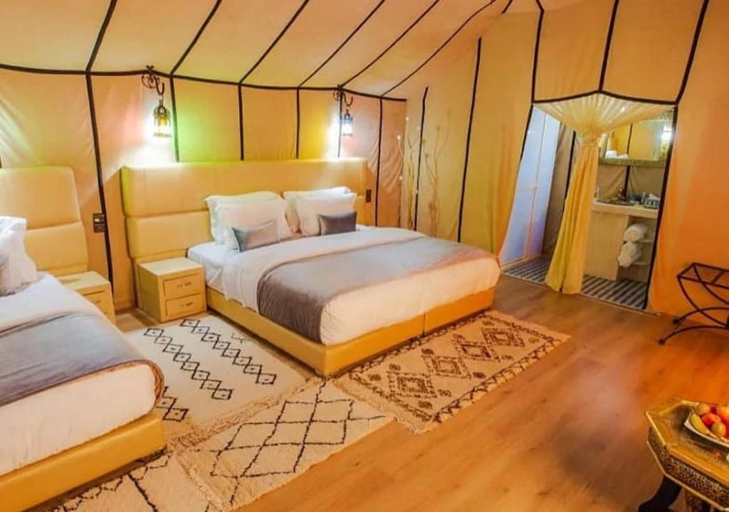 een slaapkamer met 2 bedden in een tent bij Deep Desert Camp in Merzouga