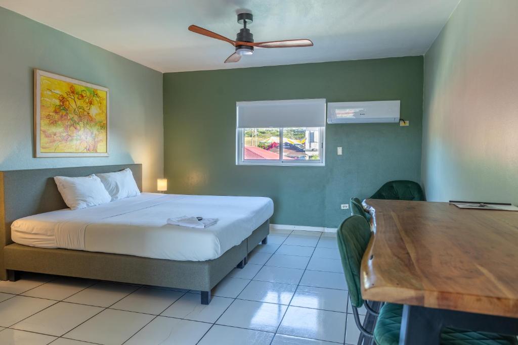 Talk of the Town Inn & Suites - St Eustatius في أورانجستاد: غرفة نوم بسرير وطاولة خشبية