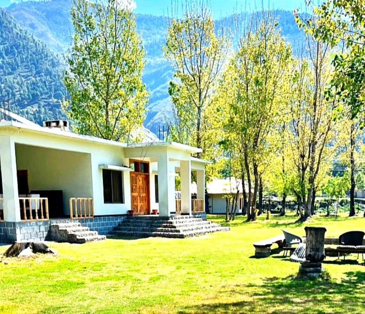 a house in a field with mountains in the background at Two-Bedrooms Suite At Country Club Balakot in Bālākot