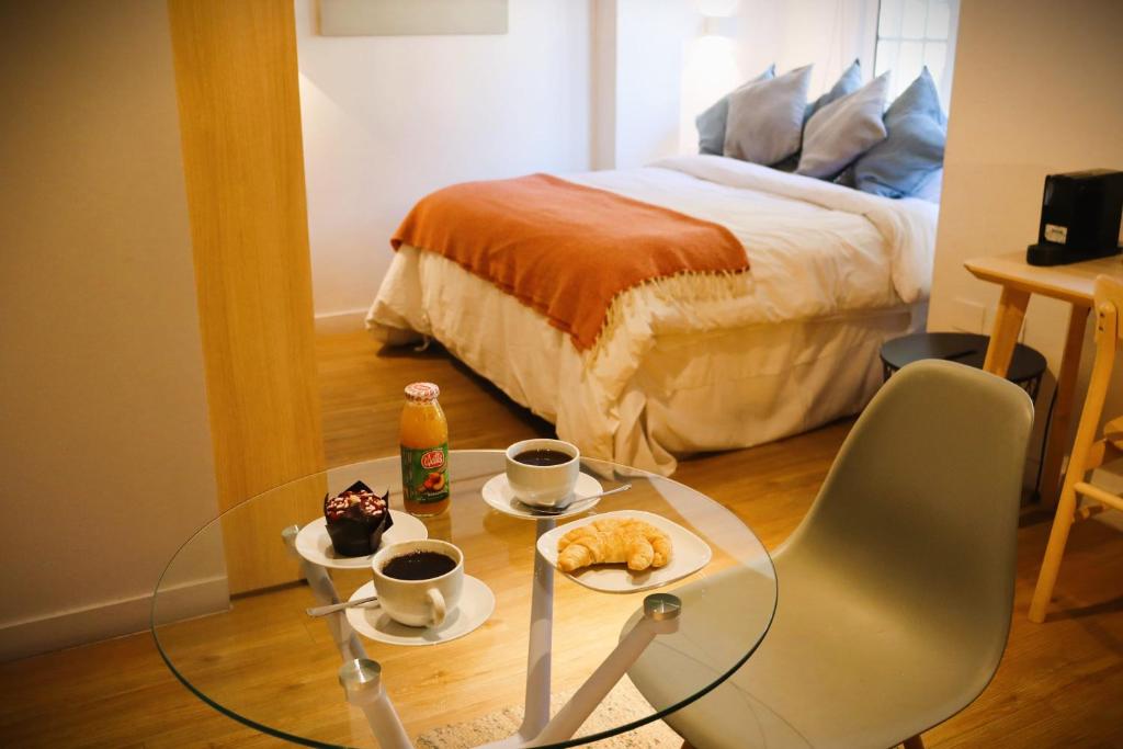 a room with a bed and a glass table with cups of coffee at Departamento con encanto en icónico Barrio Lastarria in Santiago