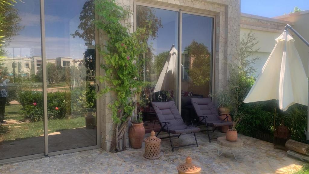 um pátio com 2 cadeiras e um guarda-sol em résidence golfique em Fez