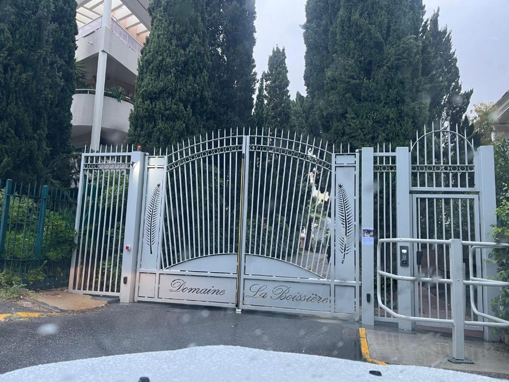 a white gate with a dog standing behind it at Agréable chambre et salle de bain privée dans notre appartement partagé in Cannes