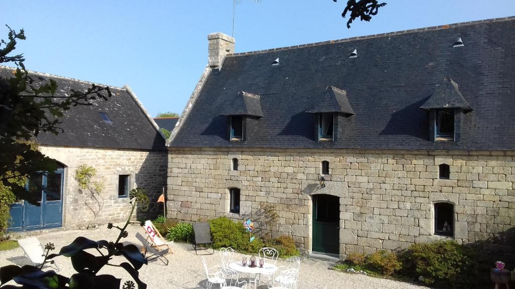 un grand bâtiment en pierre avec un toit noir dans l'établissement Belle maison au bord de la mer, à Combrit