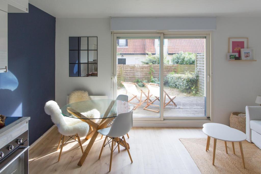 une salle à manger avec une table et des chaises en verre dans l'établissement Appartement Terrasse Jardin à 2 pas de la plage, à Wissant