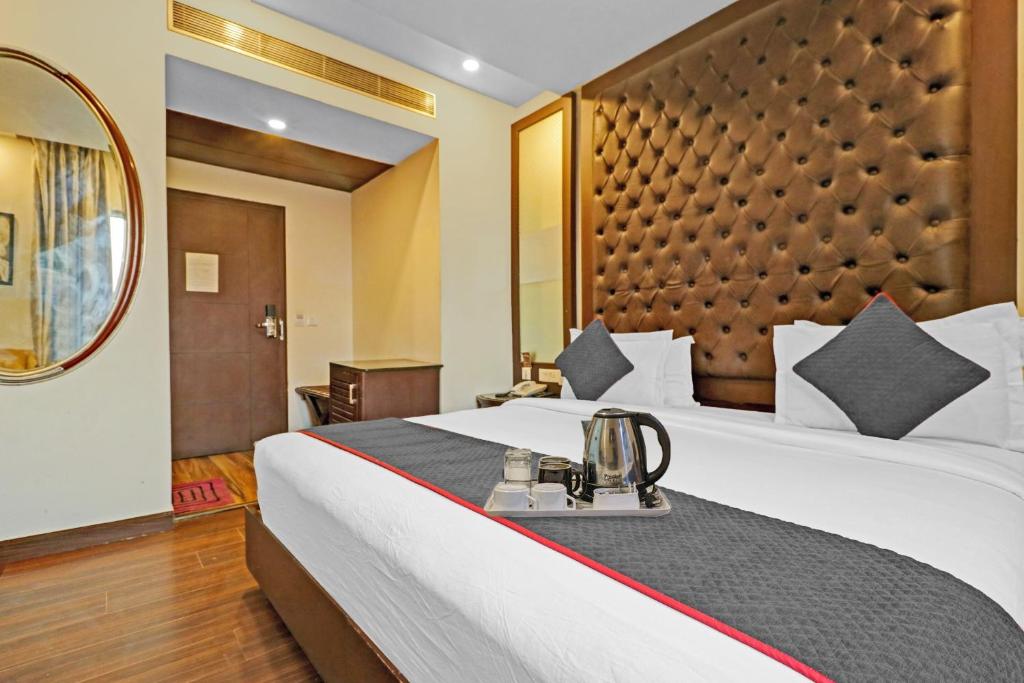 Grand Empire Suites By Delhi Airport في نيودلهي: غرفة الفندق بسرير كبير ومرآة