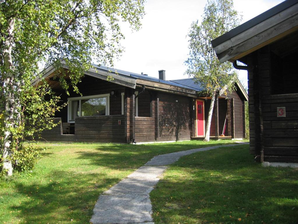 uma casa de tijolos com um jardim de relva em frente em Lullens Stugby - Stugorna 1-5 em Bruksvallarna