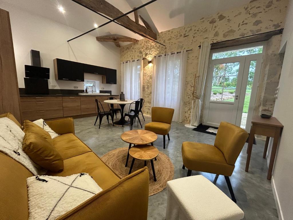 a living room with a couch and chairs and a table at Maison de vacances in Gondrin