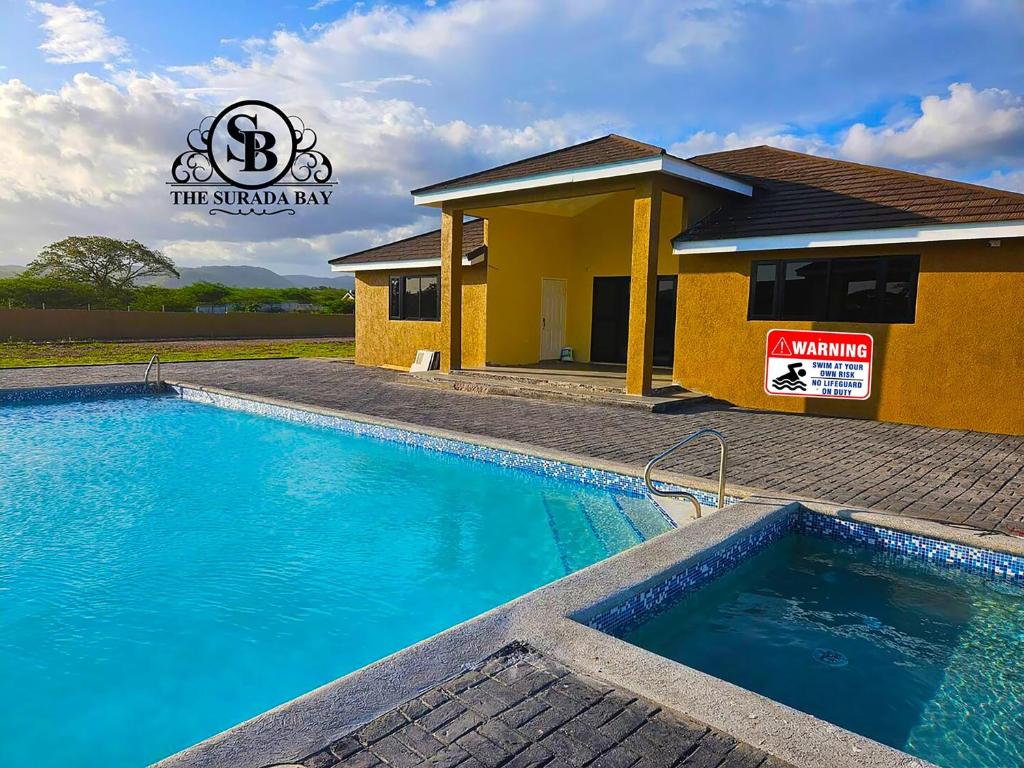 a house with a swimming pool in front of a building at The Surada Bay 2 bedrooms in Old Harbour