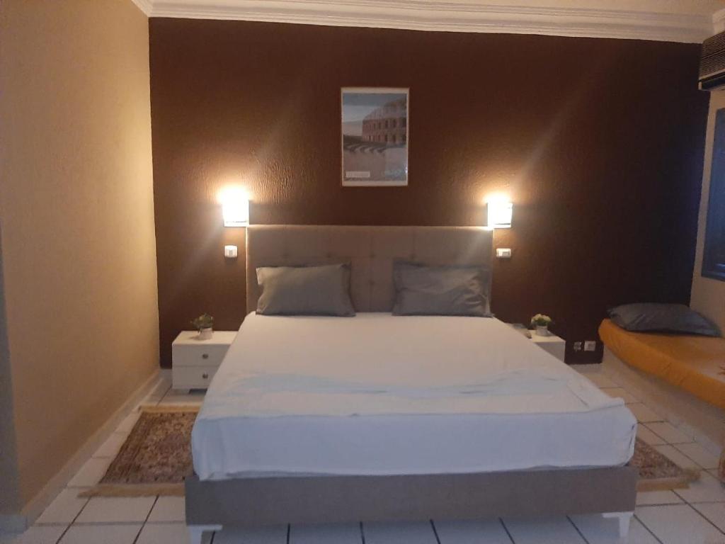 - une chambre avec un grand lit blanc et deux lumières dans l'établissement Hotel Le Khalife, à Hammamet