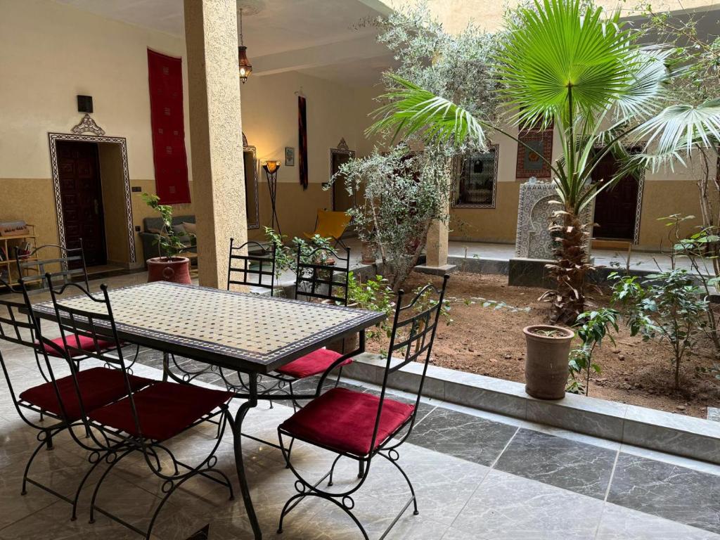 una mesa y sillas en un patio con plantas en Riad Dar Tazoulte, en Agdz