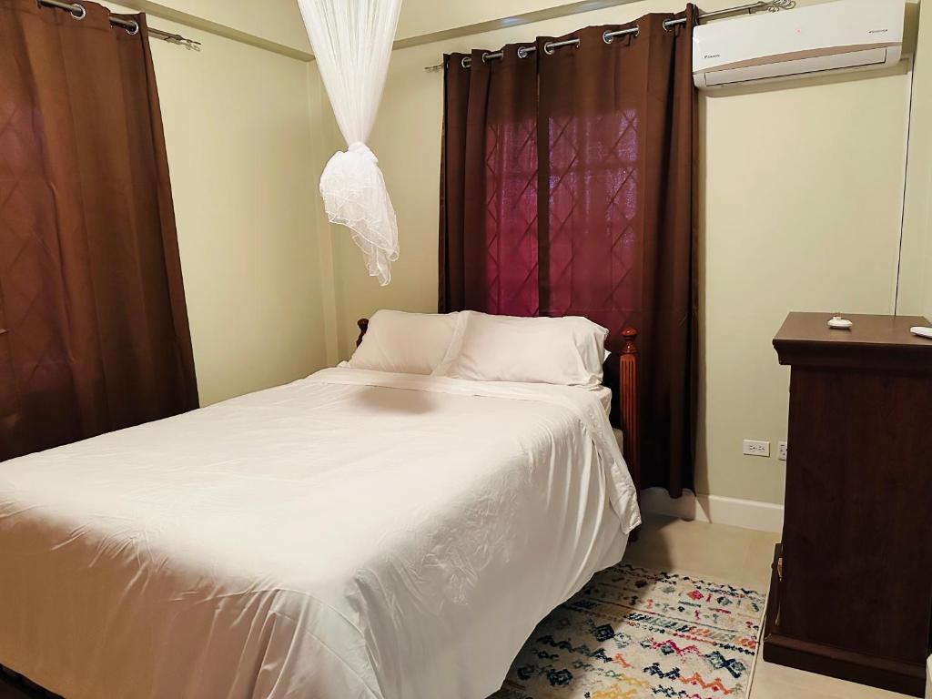 a bedroom with a white bed and a window at Fraser's Suites in Kingstown