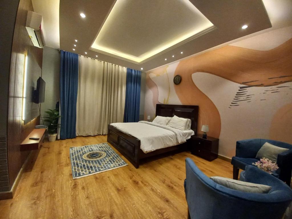a bedroom with a bed and two blue chairs at Royal Lodge By Hotel Demanchi in Murree