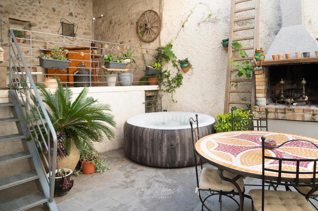 un patio avec une table et un bac avec des plantes dans l'établissement Maison atypique, grande terrasse avec jacuzzi, à Cazouls-d Herault