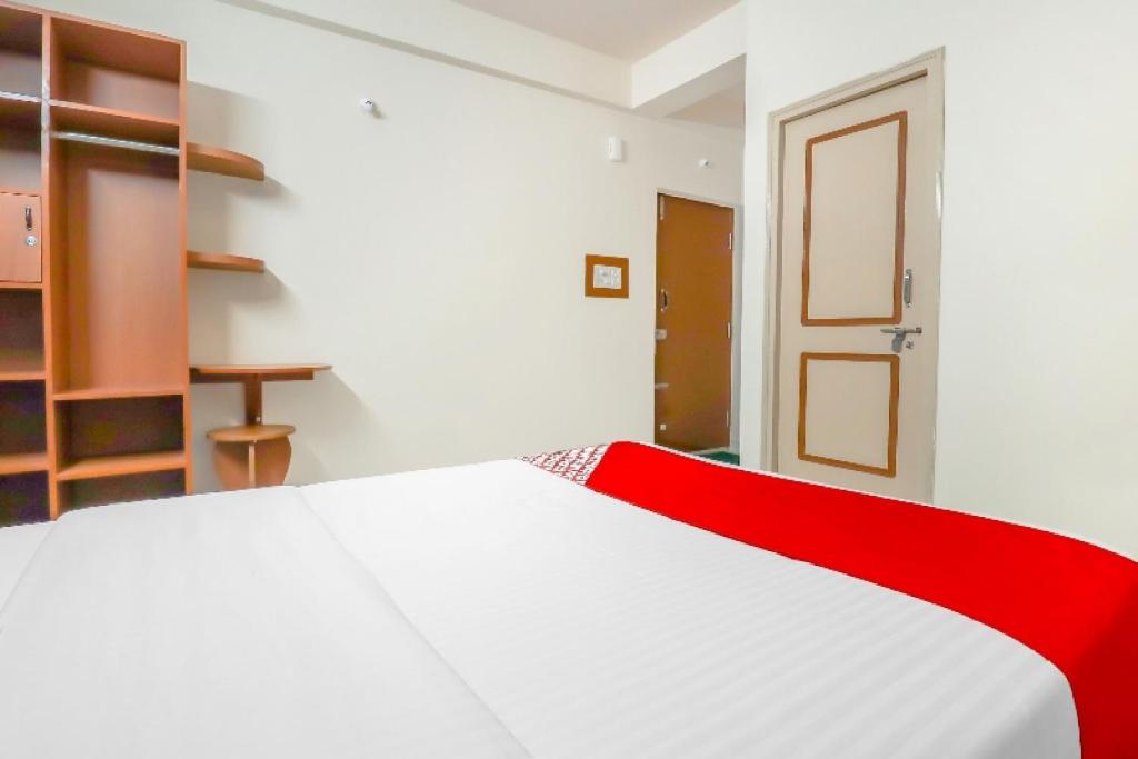 a bedroom with a white bed with a red blanket at 79522 The Host in Bangalore