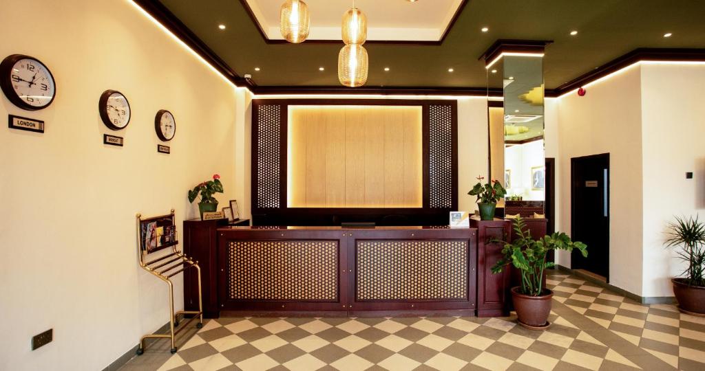 a lobby with a reception desk and clocks on the wall at Al Shorouq Hotel Apartments in Muscat