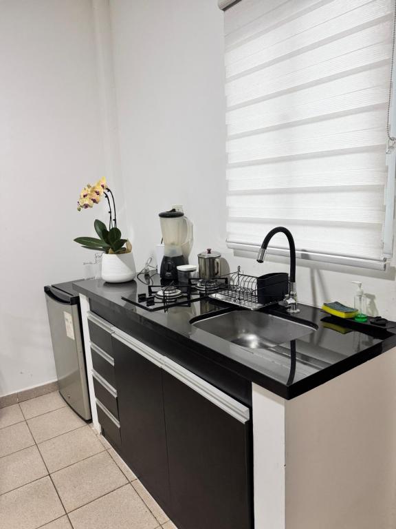 uma cozinha com um balcão preto e um lavatório em Acogedor independiente-Casa JH A em Santa Cruz de la Sierra