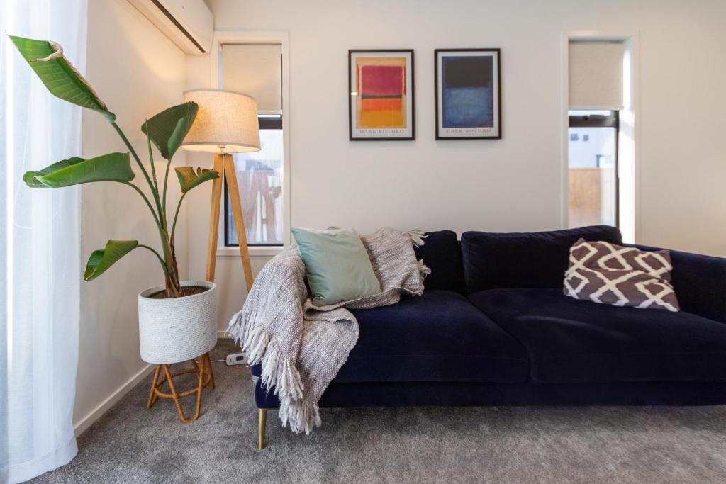 a living room with a blue couch and a plant at Serenity by the Sea: Coastal Escape1 bed 1 bath in Christchurch