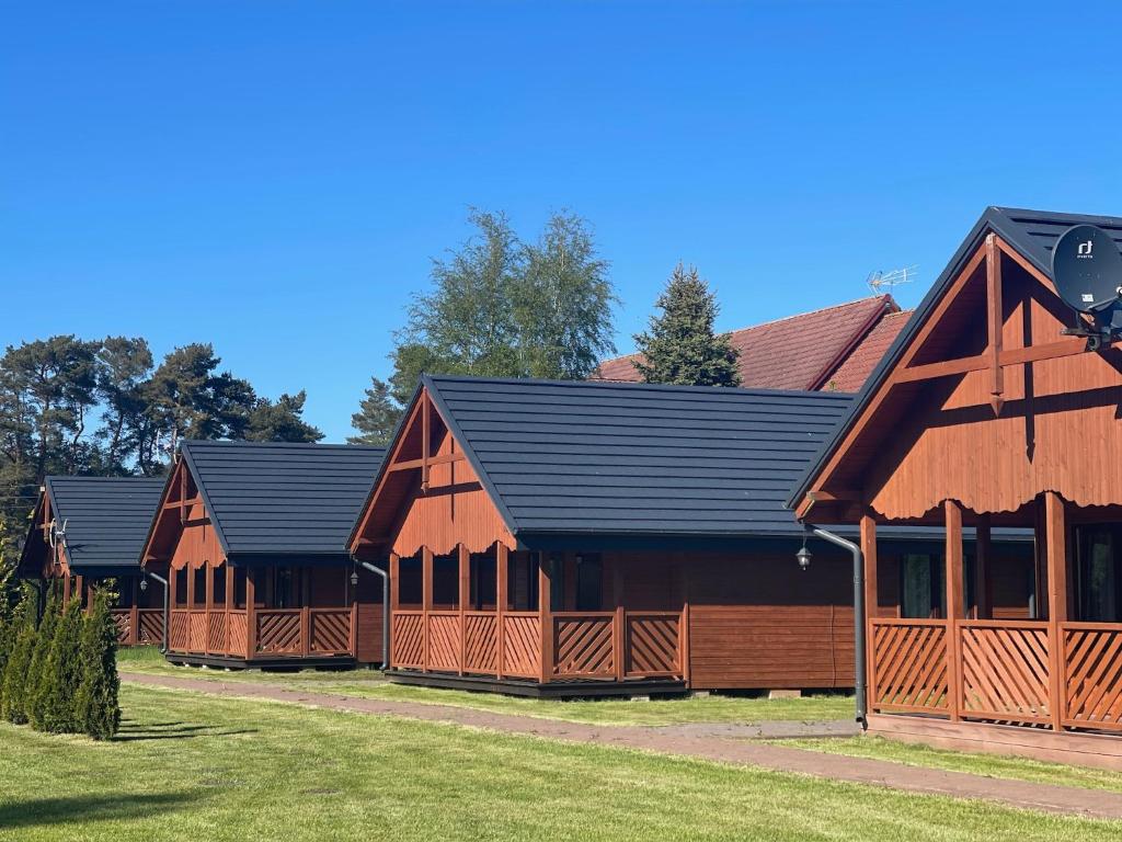 a row of wooden barns with black roofs at Domki Alex in Dębki