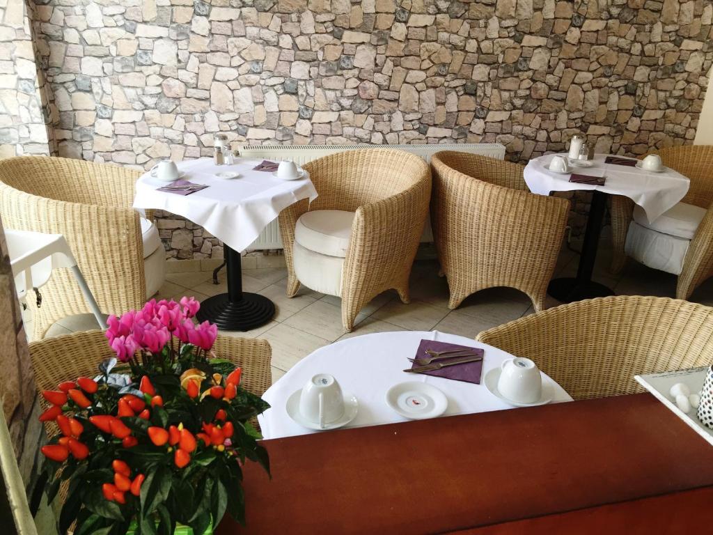 a restaurant with two tables and chairs and flowers at Hotel Ariana in Cologne